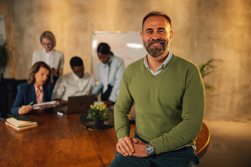 Smiling businessman looking at camera on meeting of interracial team.