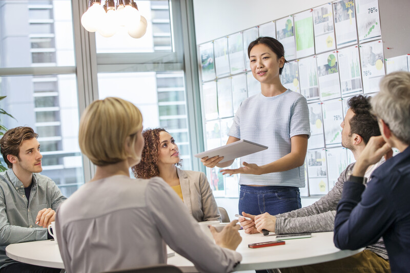 Female digital designer explaining ideas to team at conference table