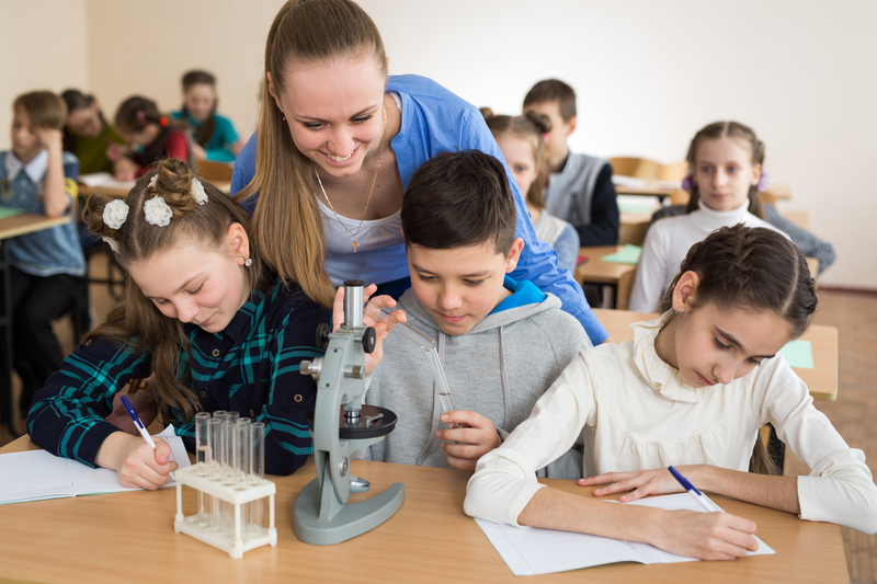 Students using science beakers and a microscope at the elementar
