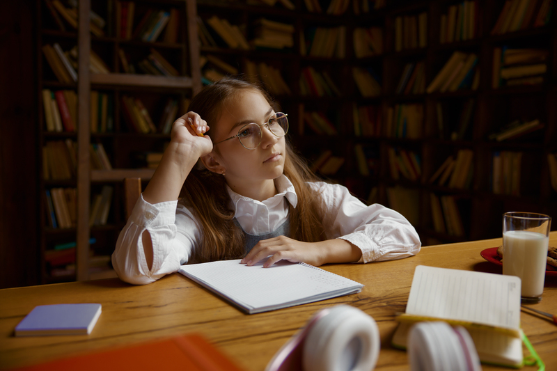 Portrait of pensive girl student doing homework or studying at desk